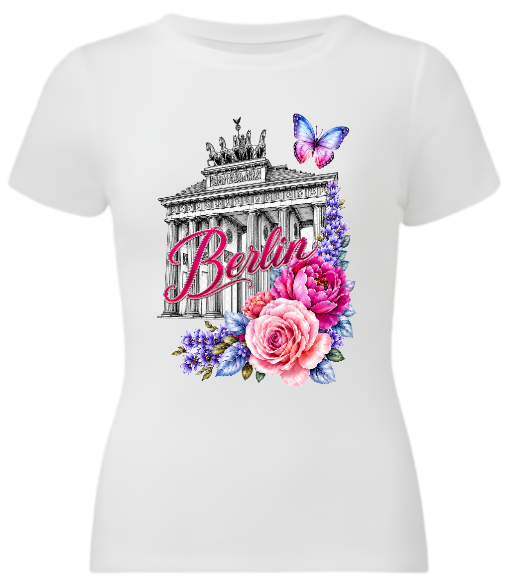 A white short-sleeve crewneck t-shirt featuring a colorful graphic print of the Brandenburg Gate with the word 'Berlin' in pink script, surrounded by pink and purple flowers and a butterfly.