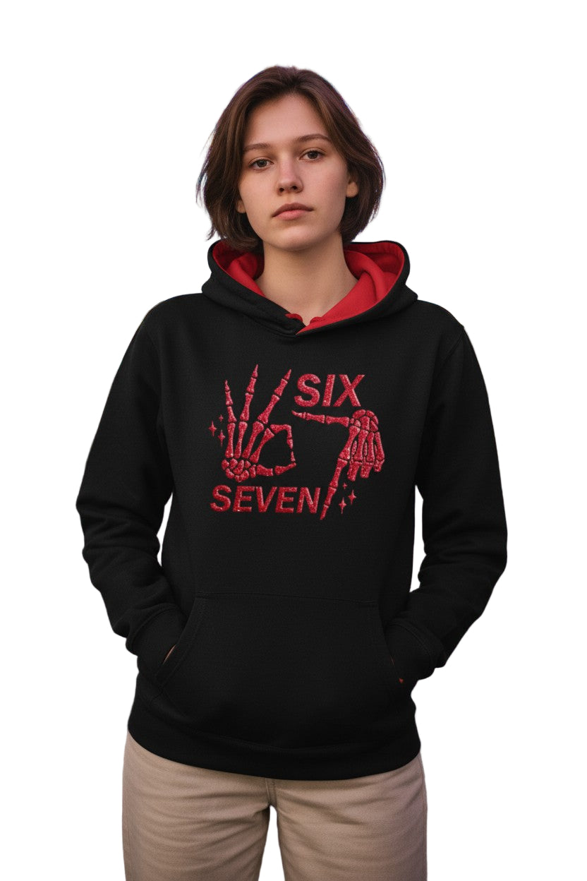 Person wearing a black hoodie with red text with 6 7 and graphics against a colorful light display background