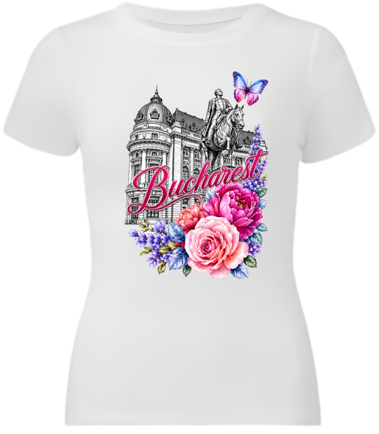 A white short-sleeve crewneck t-shirt featuring a colorful graphic print of the Budapest skyline, including the Buda Castle, a statue, a butterfly, and pink and purple flowers with the word 'Budapest' in script.