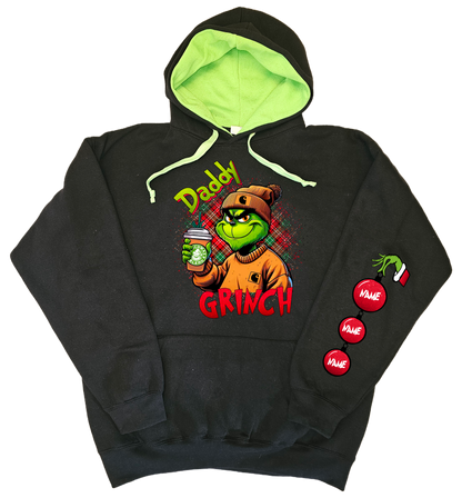 A black hoodie with a green hood, featuring a cartoon character illustration of 'Daddy Grinch' and Christmas tree globe ornaments on the sleeves.