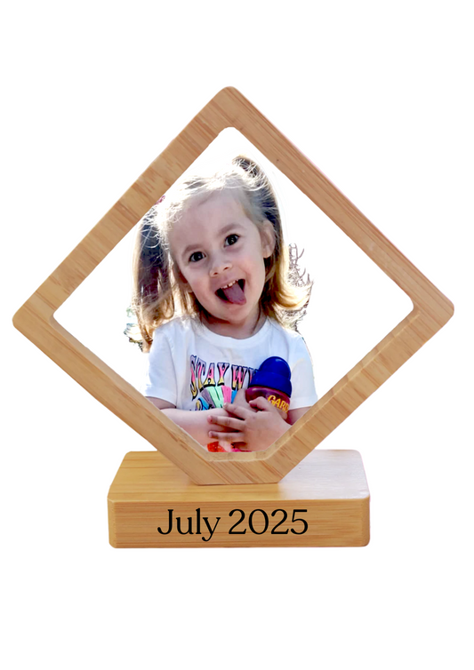 Wooden photo frame with a child's picture and 'July 2025' text on a colorful background.