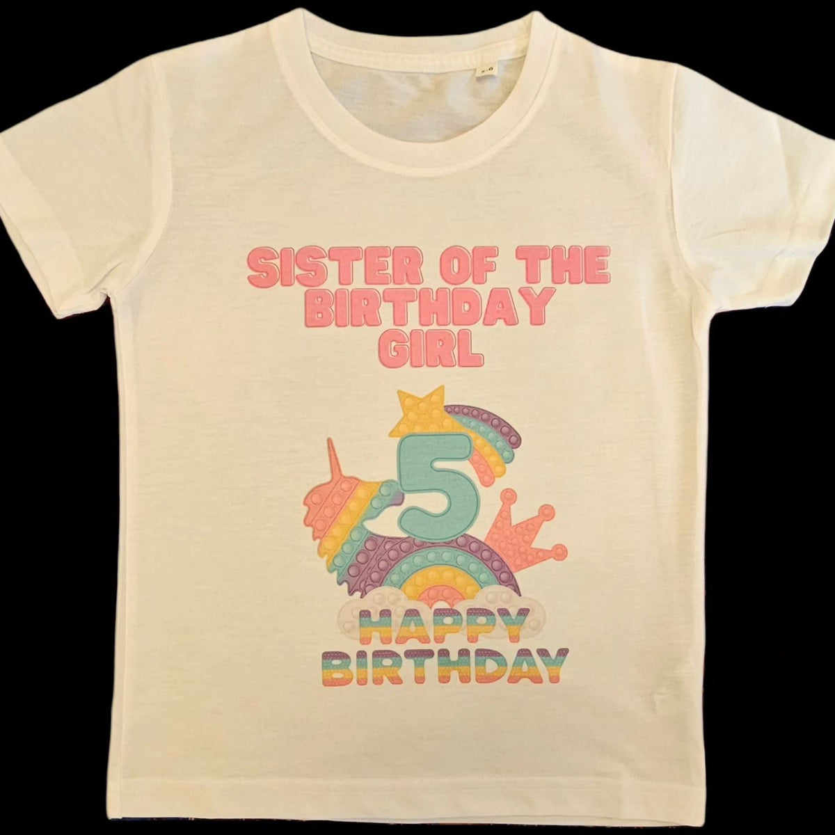 A white t-shirt with a colorful 'Pop It' design and text celebrating a birthday, featuring the number 5 and the phrase 'Sister of the Birthday Girl'.