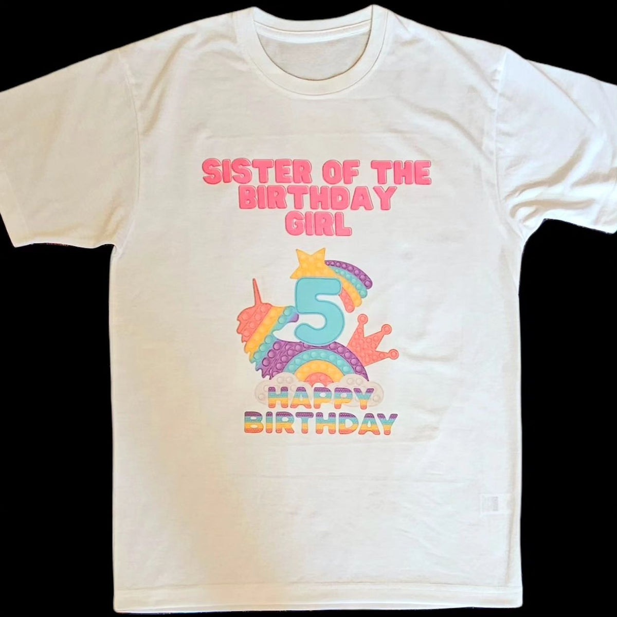 A white t-shirt with a colorful 'Pop It' design and text celebrating a birthday, featuring the number 5 and the phrase 'Sister of the Birthday Girl'.