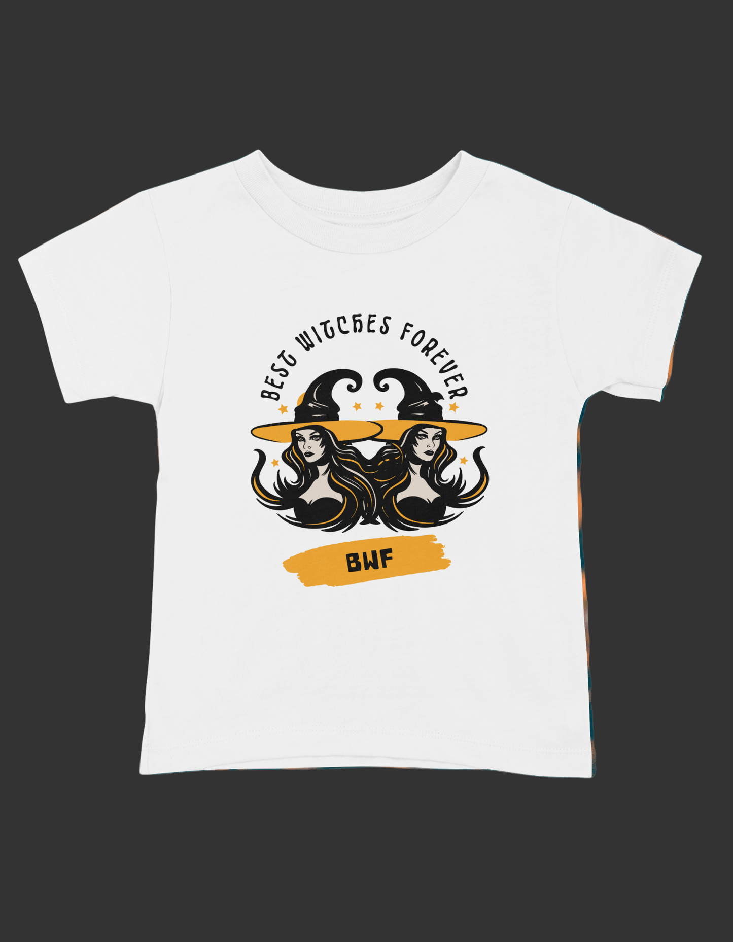 A white short sleeve t-shirt with a graphic print that reads 'Best Witches Forever' and includes images of two witch hats and a cauldron, surrounded by a fiery background.